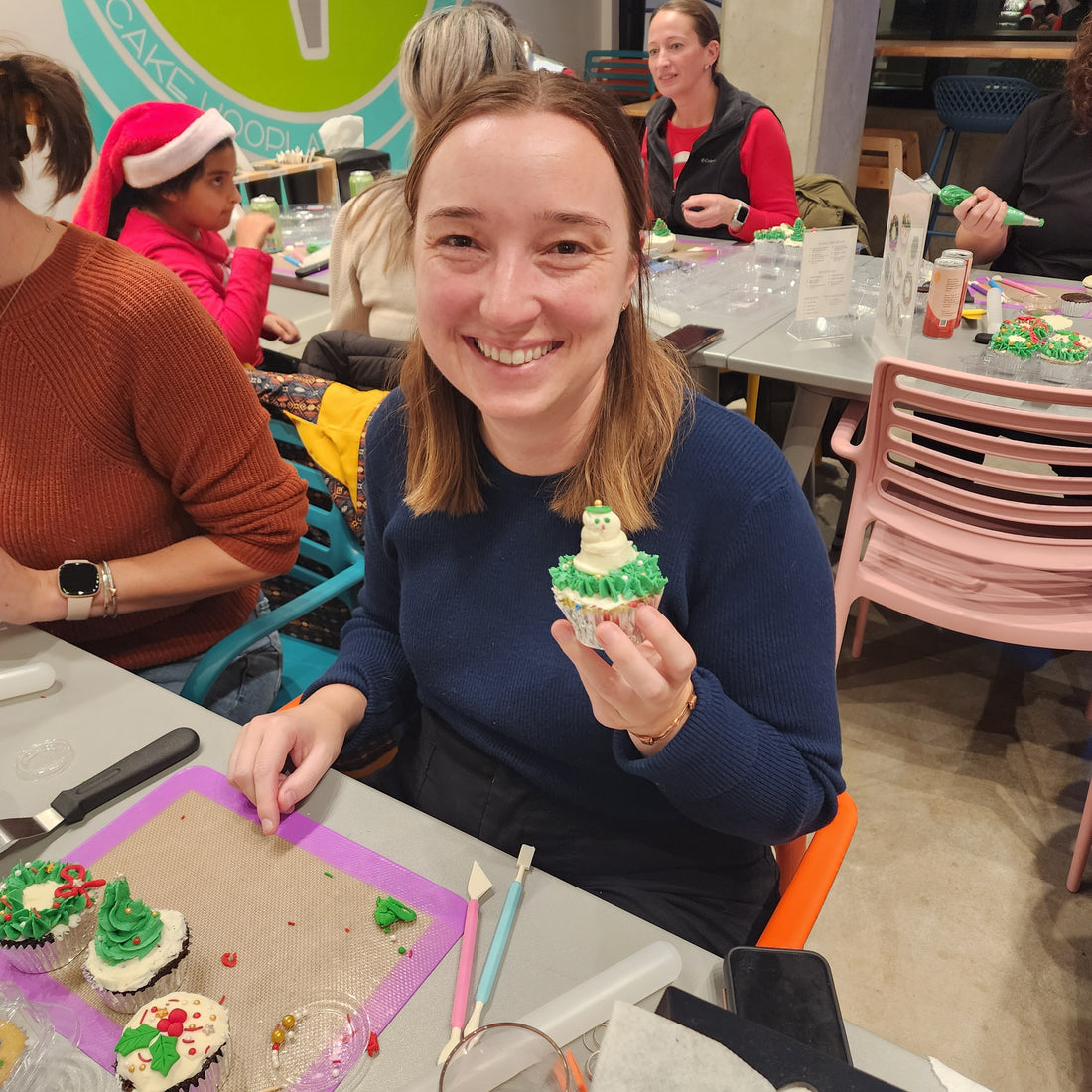 a smiling woman shows off her holiday cupcake decorated at Cake Hoopla in Tigard, Oregon