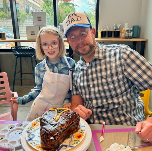 Young girl and her father decorating a cake during open studio time at Cake Hoopla