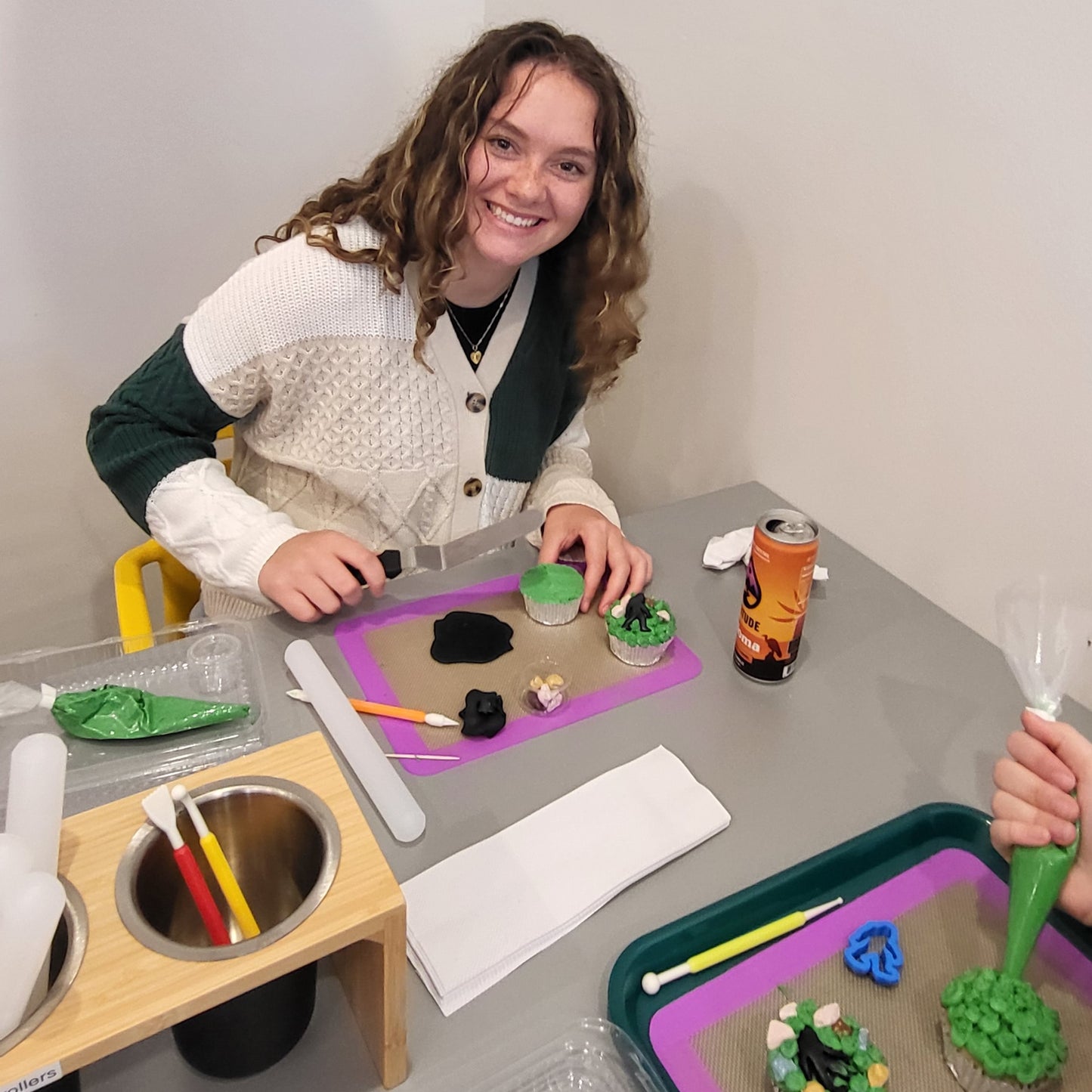 A young customer decorates cupcakes with green frosting and a black fondant bigfoot at Cake Hoopla's DIY cake/cupcake-decorating studio.