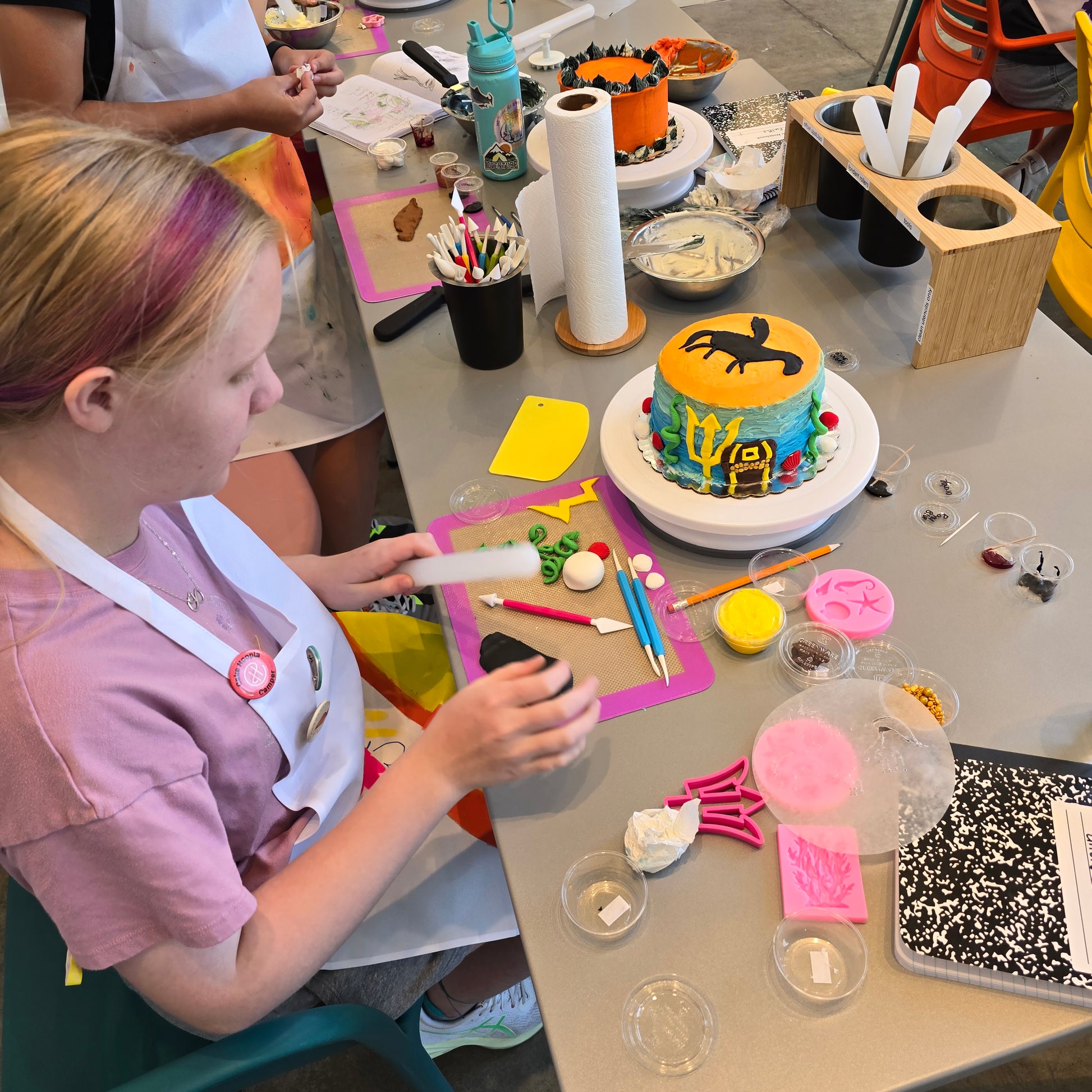 A girl decorates a Percy Jackson themed cake during summer cake camp at Cake Hoopla in Tigard, Oregon near Portland.