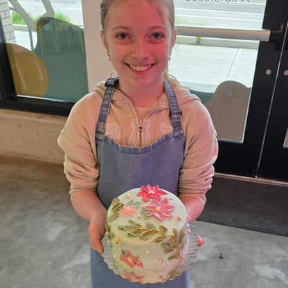 A girl shows off the cake she decorated with pallet knife flowers and frosting at Cake Hoopla in Tigard, Oregon near Portland.