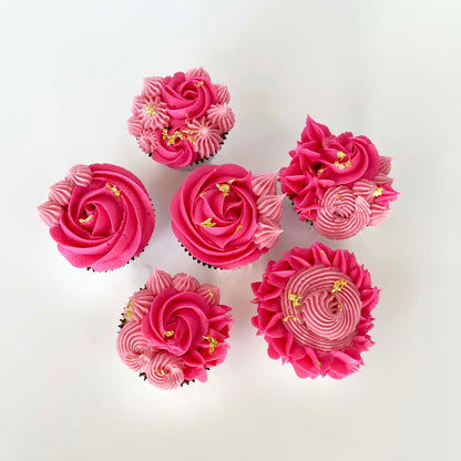 Pink floral-themed cupcakes decorated with light and dark pink rosettes and stars and gold leaf; a DIY cupcake kit available to decorate during open studio time at Cake Hoopla in Tigard, Oregon, in the Portland area.