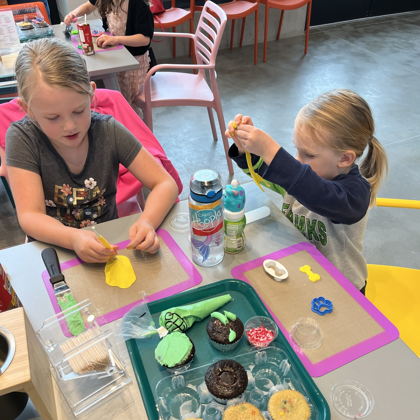 two little girls decorate cupcakes with fondant and frosting