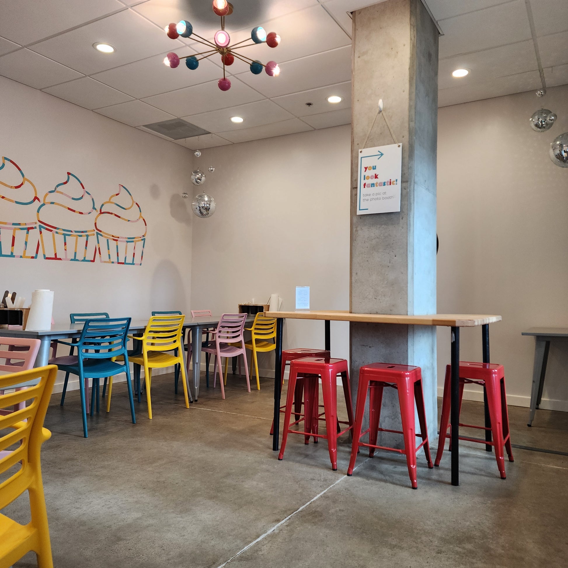 Cake Hoopla party room with bright, vibrant colored chairs, lighting, disco balls, an wall mural.