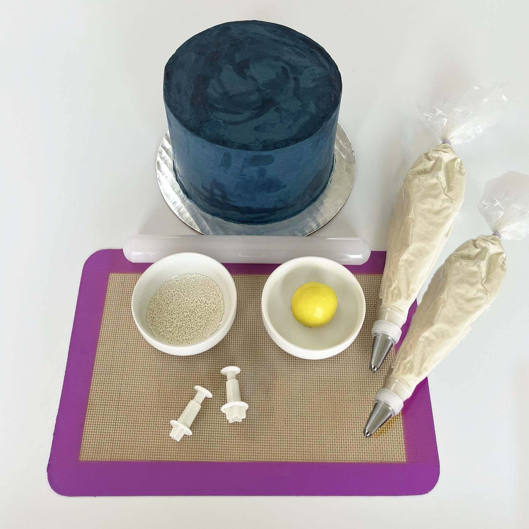 Picture of DIY cake kit To the Moon, including a dark blue cake, yellow fondant, white sprinkles, and white frosting, available for decorating during open studio time at Cake Hoopla near Portland.