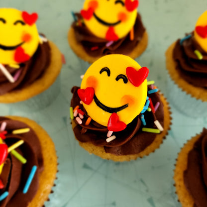 Two finished cupcakes from the Happy Hearts Emoji DIY cupcake-decorating kit available for open studio time, as a to-go kit, or as pre-decorated cupcakes from the Cake Hoopla in Tigard, Oregon near Portland