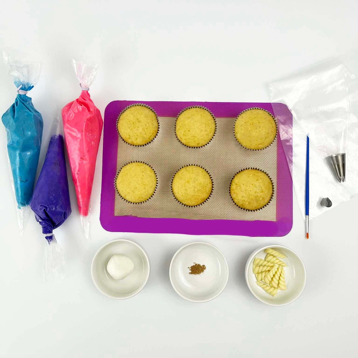 Components of Mythmaker DIY cupcake-decorating kit with blue, purple, and pink frosting, white fondant, tools, and edible gold paint available as a kit for open studio time or to-go from Cake Hoopla in Tigard, Oregon near Portland.